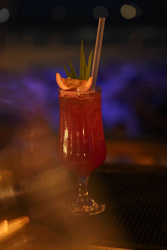 Close-up of Casa Bay signature red cocktail with purple bokeh background